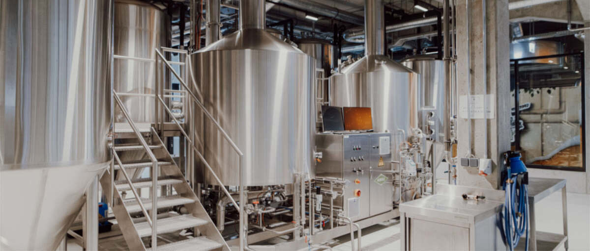 Moderne Brauanlage in der Hopfenfänger Brauerei mit großen Edelstahl-Gärtanks, Leitungen und Steuerungstechnik