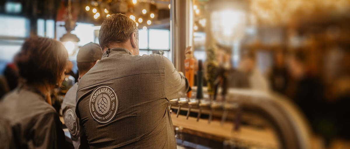 Hopfenfänger Mitarbeiter in Brauerei-Uniform zapft Bier an der Theke während einer Veranstaltung in Bremen